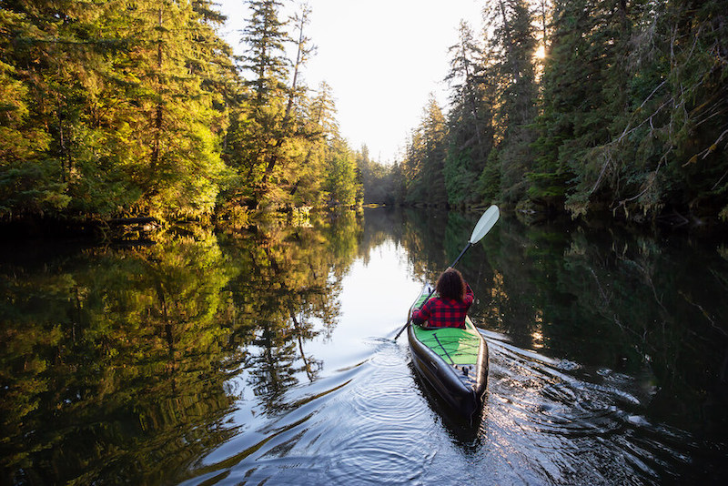 Fille faisant du kayak sur l'eau en camping sauvage