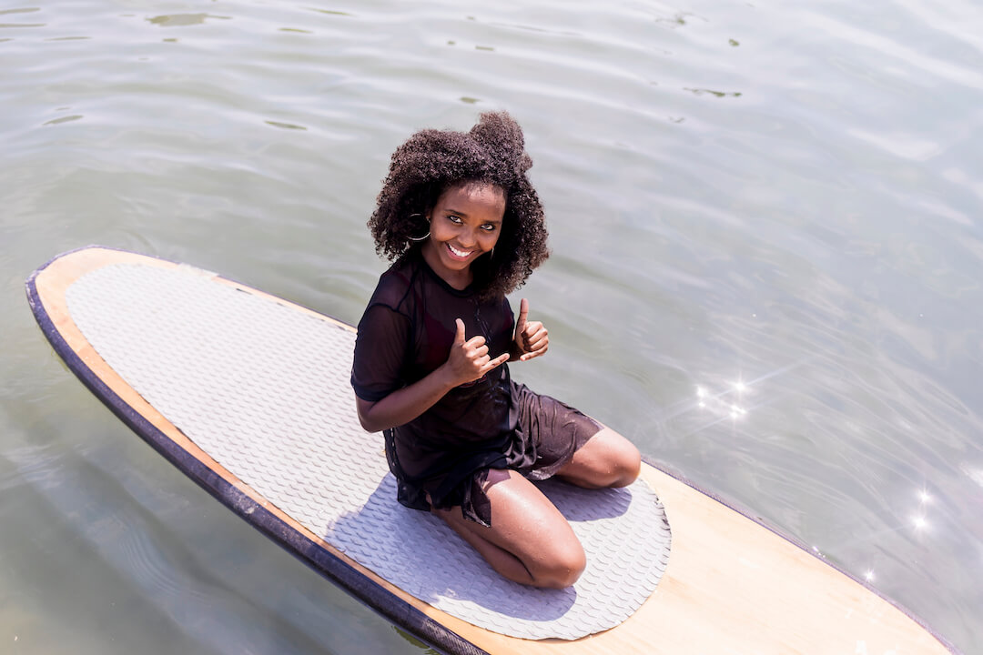 Jeune fille assise sur une planche à pagaie sur l'eau